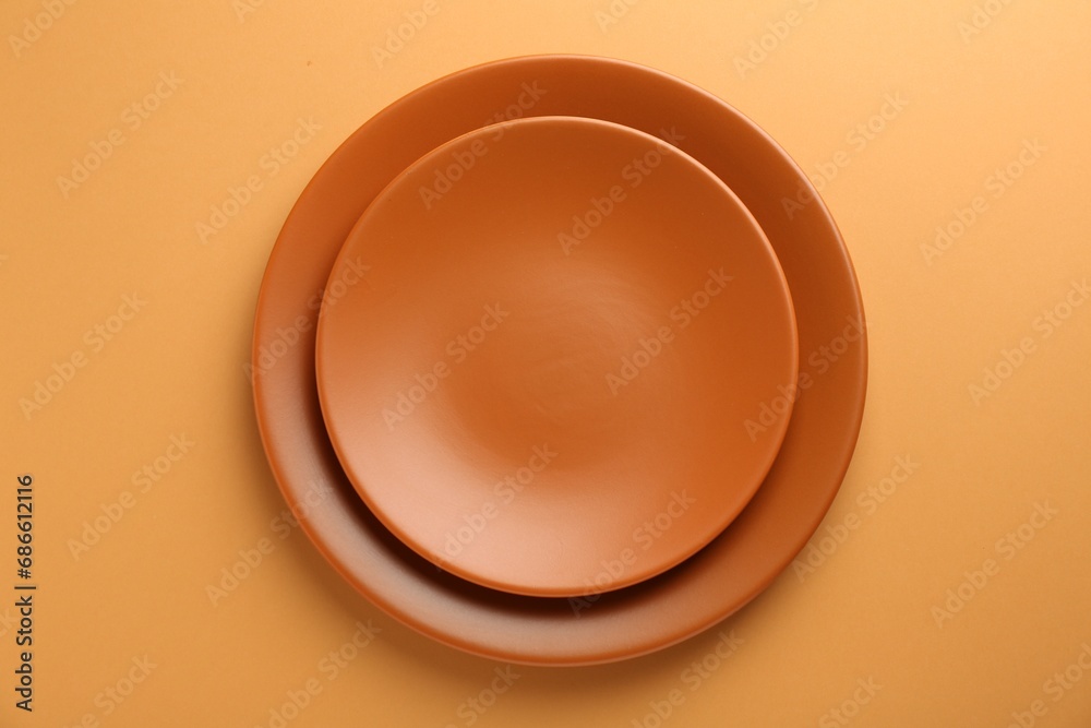 Beautiful ceramic plates on orange background, top view Beautiful ceramic plates on orange background, top view