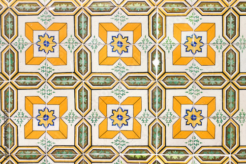 Antique tile with yellow, green, ochre, blue and black motifs on a white background (Lisbon)