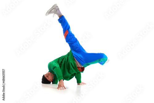 Stylishly dressed man performing freestyle, breakdance, standing on hands raised up legs against white background. Swipe.
