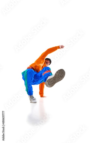 Young flexible sportive man dancing breakdance in vivid orange and blue sport uniform outfit against white studio background.