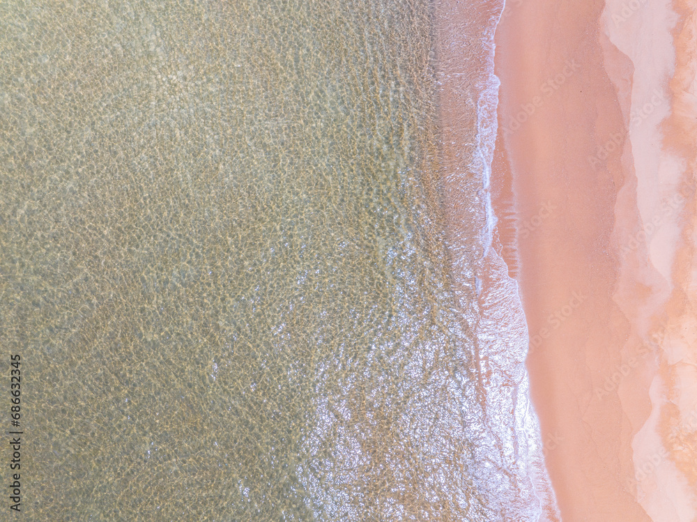 Fototapeta premium Aerial view of sea crashing waves White foaming waves on beach sand,Top view beach sea surface, Nature sea beach sand background