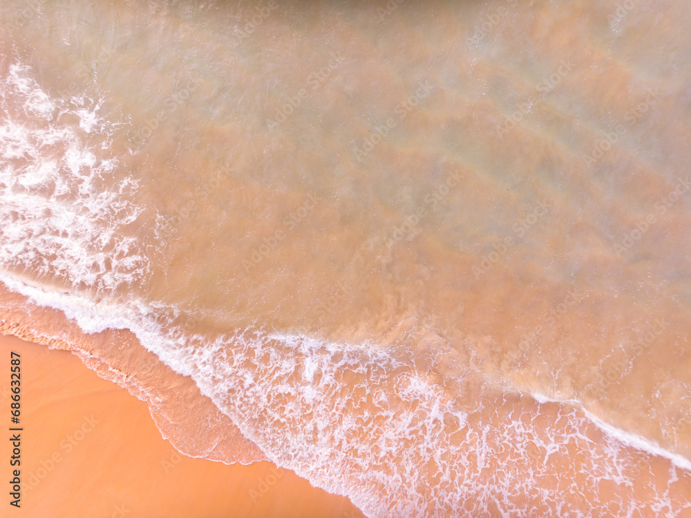 Fototapeta premium Aerial view of Waves crashing on sandy shore,Sea surface ocean waves background,Top view beach background