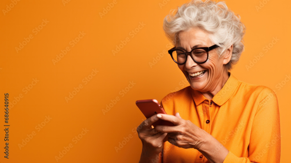 Happy senior woman waving on video call through smart phone against orange background - obrazy, fototapety, plakaty 