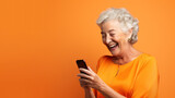 Happy senior woman waving on video call through smart phone against orange background