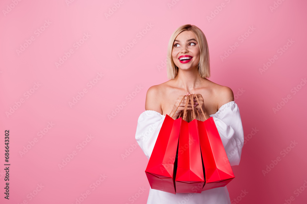 Photo of pretty lovely girl dressed white clothes holding shopping bags look at promo empty space isolated on pink color background Photo of pretty lovely girl dressed white clothes holding shopping bags look at promo empty space isolated on pink color background
