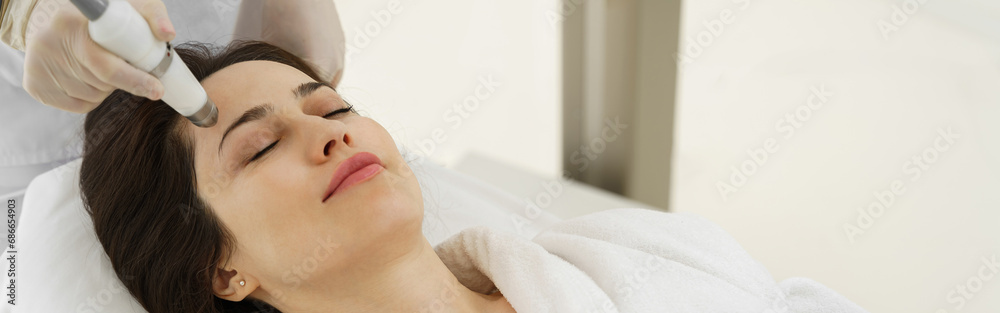 Naklejka premium Cosmetologist making ultrasound cavitation anti-aging and lifting procedure for woman in spa center