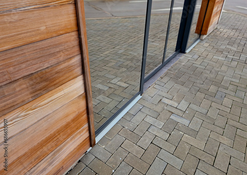 glass door to shop with mirror reflective window surface. automatic door to the restaurant with wooden cladding. photo