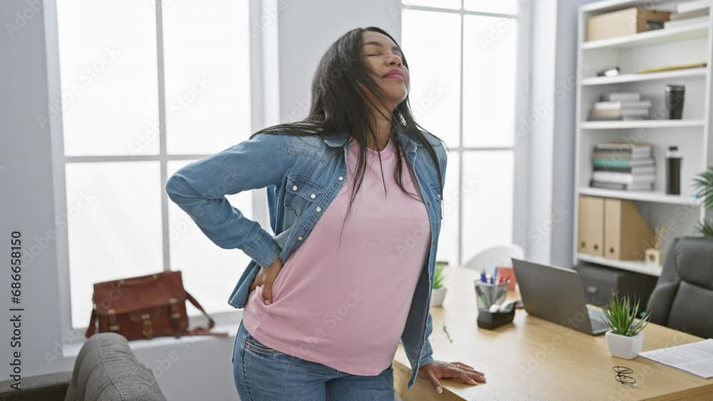 Young pregnant business worker lady suffering backache whilst trying to catch her breath in the office Young pregnant business worker lady suffering backache whilst trying to catch her breath in the office