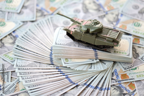 Toy tank on US hundred dollar bills banknotes close up. The concept of war costs, military spending and economic crisis photo