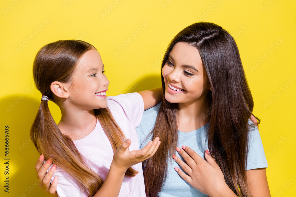 Photo of excited adorable small siblings dressed t-shirts cuddling communicating isolated yellow color background Photo of excited adorable small siblings dressed t-shirts cuddling communicating isolated yellow color background