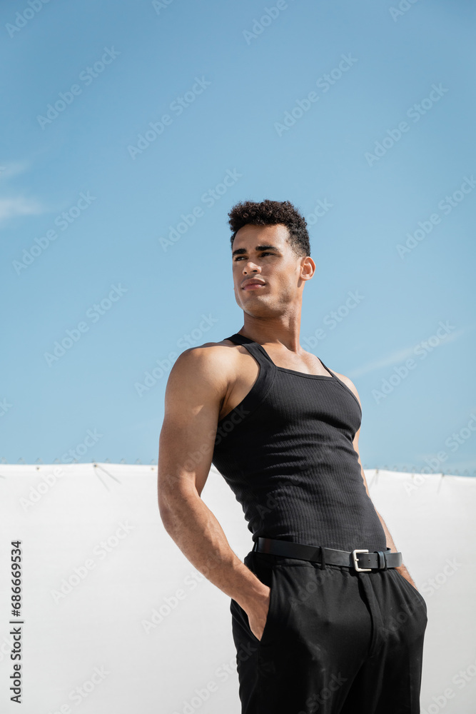 Fototapeta premium muscular young cuban man in black sleeveless t-shirt and pants posing in Miami, south beach