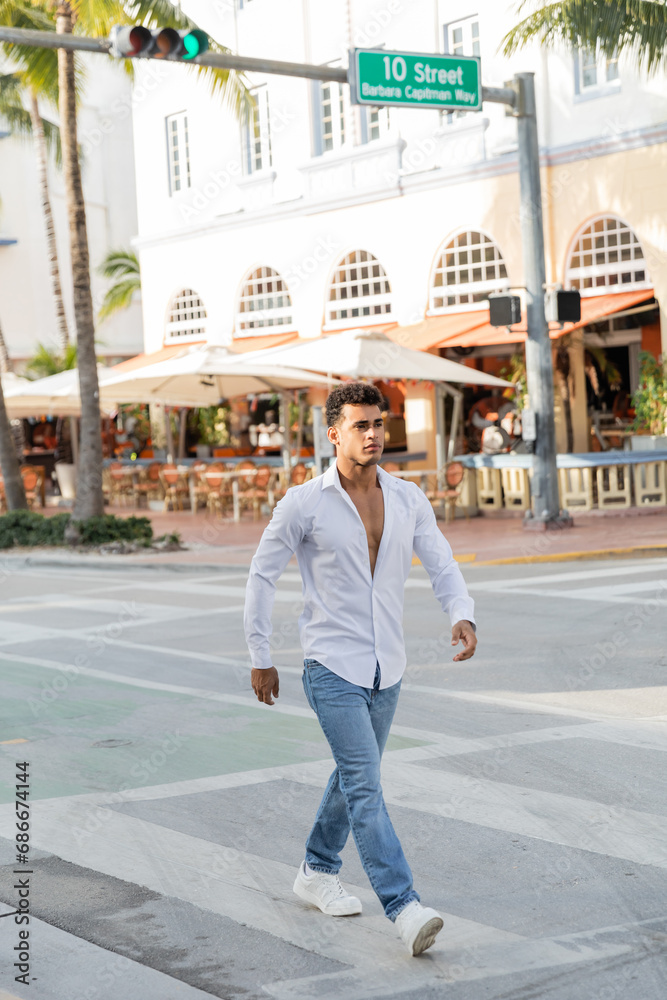 young cuban man in shirt and jeans walking on urban street in Miami, south beach