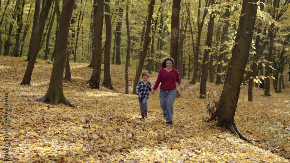 Happy Mother and Son Enjoying a Playful Moment Running Through a Pile of Golden Autumn Leaves in the Park. High quality 4k footage Happy Mother and Son Enjoying a Playful Moment Running Through a Pile of Golden Autumn Leaves in the Park. High quality 4k footage