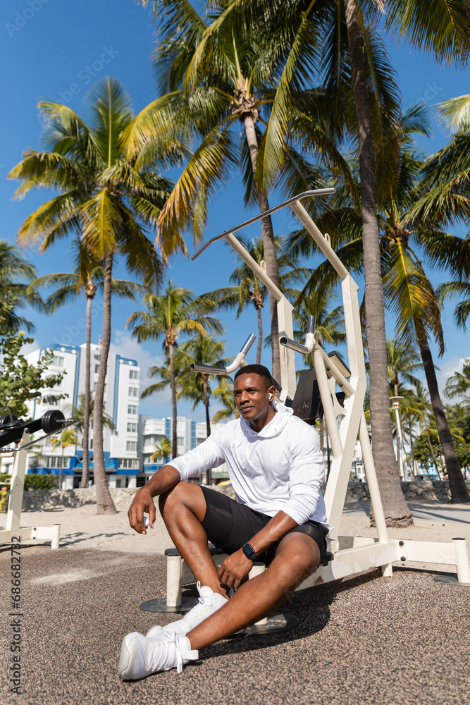 african american sportsman in wireless earphone resting after workout in Miami beach