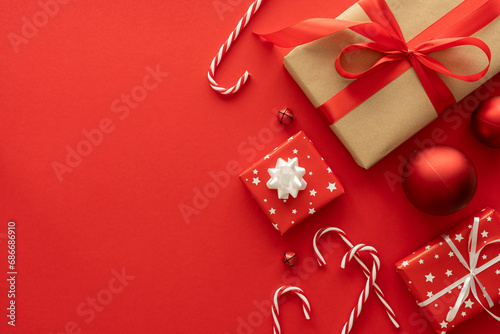 Christmas gifts, baubles ornaments, candy canes decorations. Festive presents composition. Wrapped present boxes flat lay, with copy space on red background. Winter holiday season gift guide concept.