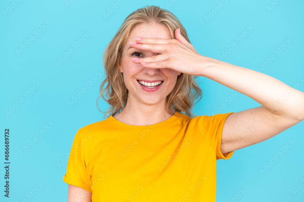 Smiling woman covering face with hand and peeping out fingers Smiling woman covering face with hand and peeping out fingers
