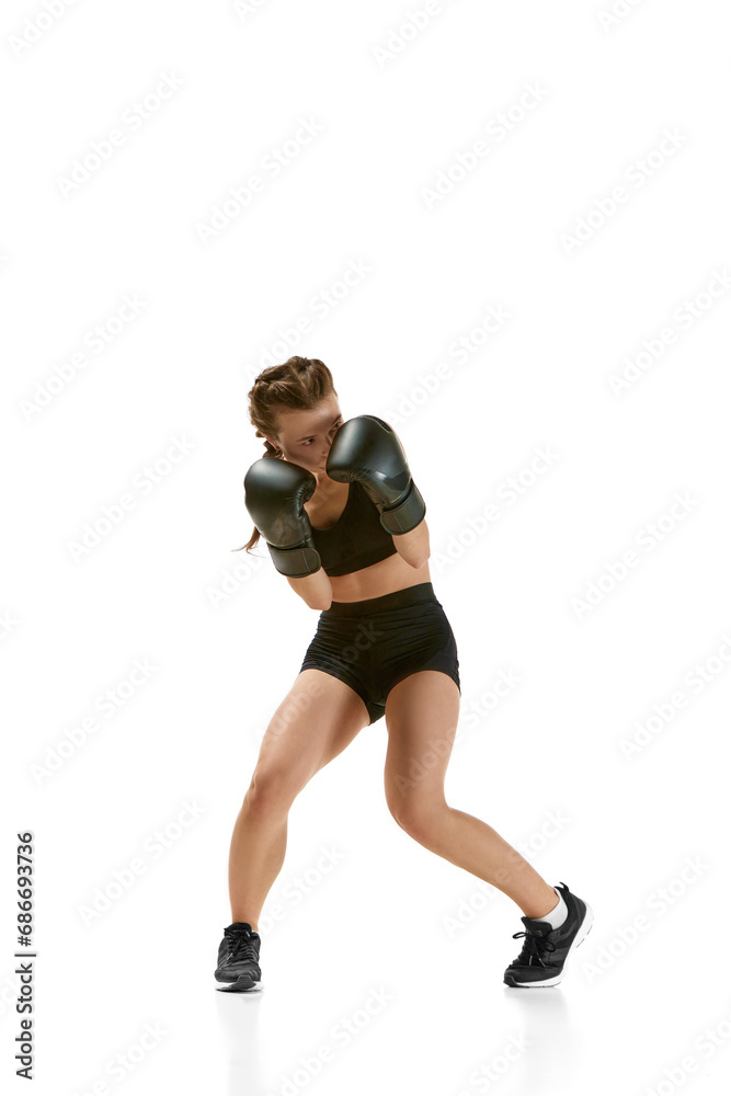 Athletic prowess and intensity captured in portrait of female boxer, professional sportsman against neutral white studio background. Athletic prowess and intensity captured in portrait of female boxer, professional sportsman against neutral white studio background.