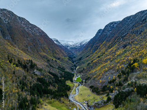 An aerial view of a canyon through which a river flows  with symmetrically arranged mountains facing each other in Norway