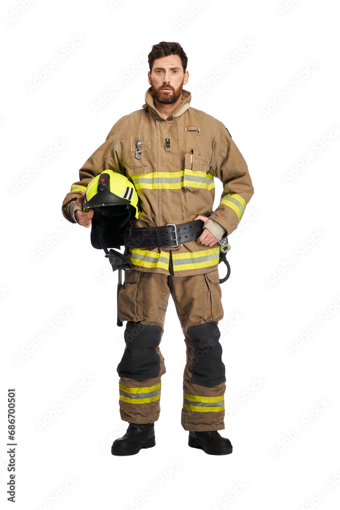 Serious bearded firefighter in uniform holding protective helmet in studio. Front view of middle aged male fireman with safety helmet, isolated on white studio background. Workplace, job concept.
