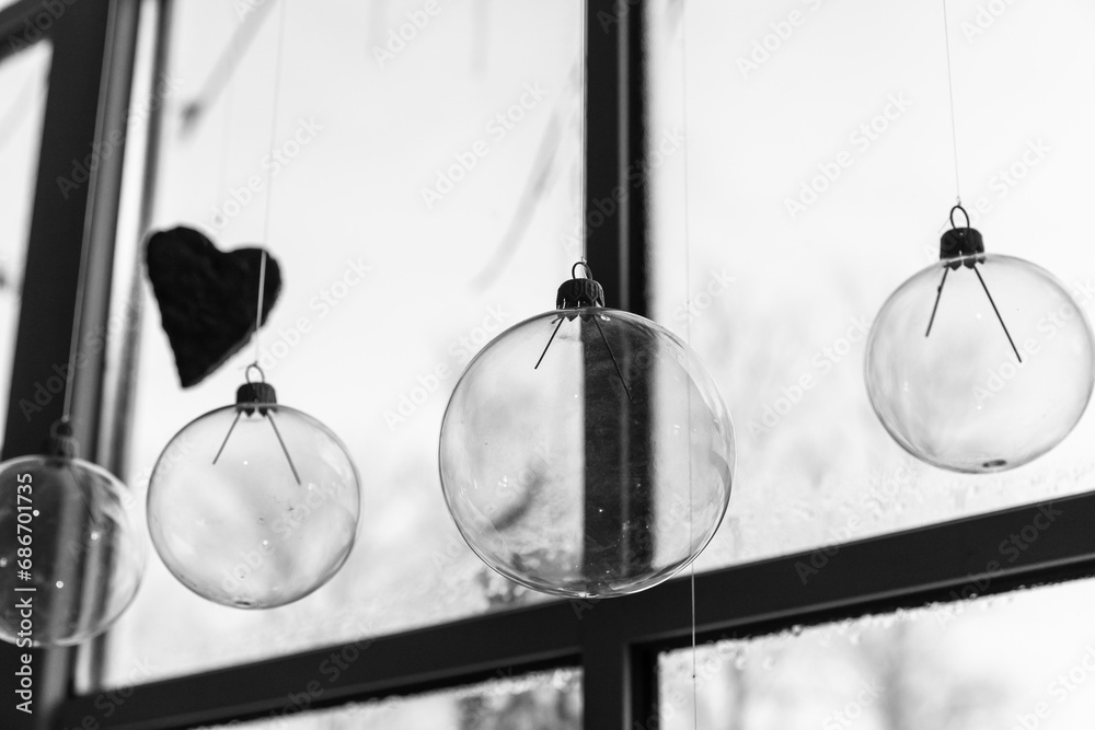 Transparent glass balls hang in front of a window, Christmas decoration
