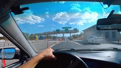 ISTANBUL, TURKEY - SEPTEMBER 2, 2023: First-person view of car e through windshield passing automatic toll terminal in turkey HGS. Driver's hands holding steering wheel. photo