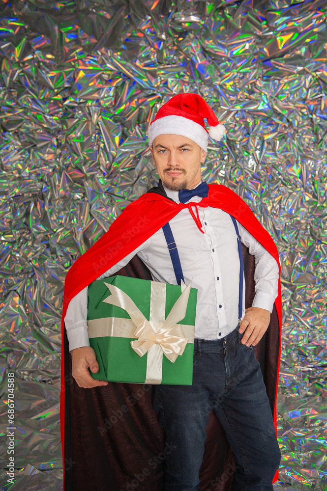 Fototapeta premium Young handsome smiling man with Christmas gift box on the sparkle background