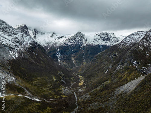 aerial view over valley in mountains with snowy peaks with flowing river