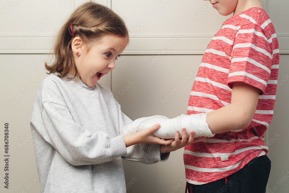 Boy broken arm, girl is in shock. Child girl holding his brother's broken arm. Boy holds hand