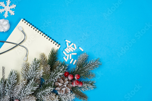 Medical Christmas blue greeting card with space for text, Christmas tree branch and notebook with stethoscope photo