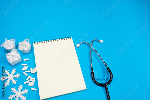 Christmas and New Year Medical Greeting Card, Notebook with Space for Text, Blue Background, Top View. photo