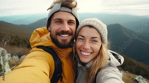 Young hiker couple taking selfie portrait on the top of mountain - Happy guy smiling at camera - Tourism, sport life style and social media influencer concept.