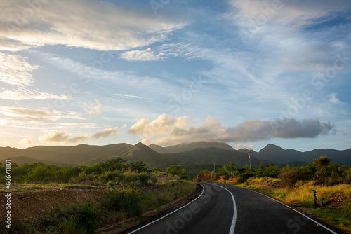 Sunrise in the desert. Tour of a desert island, full of xeric vegetation. Cactus and red earth. Mountains, clouds and sun photo