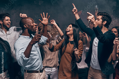 Joyful young people toasting with champagne and dancing while enjoying celebration in night club