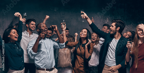 Happy young people toasting with champagne and dancing while enjoying celebration in night club