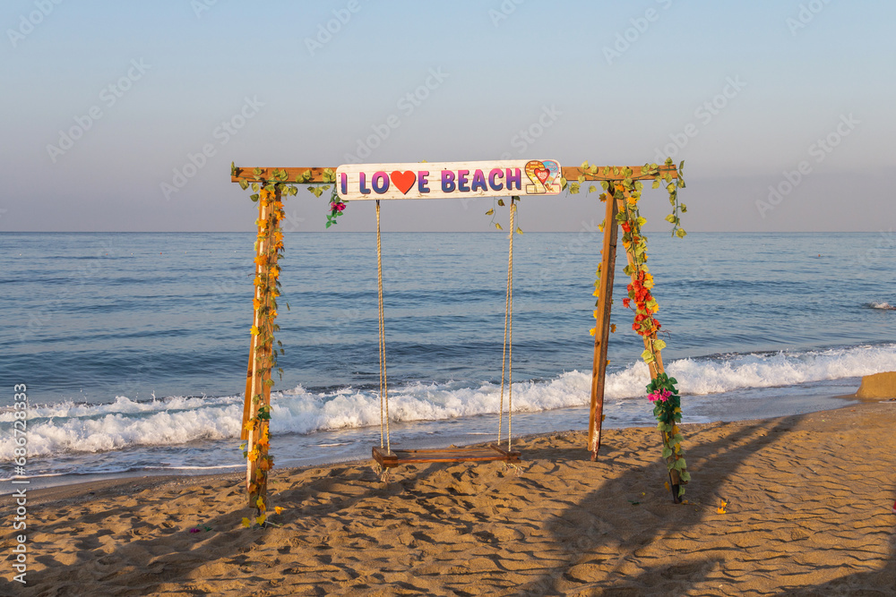 Beautiful swing on Cleopatra beach in Alanya (Türkiye). A swing on the shore of the Mediterranean Sea with the inscription Beautiful swing on Cleopatra beach in Alanya (Türkiye). A swing on the shore of the Mediterranean Sea with the inscription