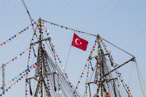 Turkish flag on the mast of a ship. The mast of the ship is decorated with multi-colored flags. Excursion on ships in Turkey.