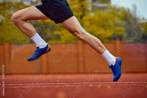 Focused sprinter on the verge of takeoff. Side view cropped photo of professional sportsman fast running on sport field to break high jump record.