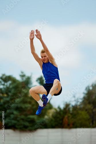 Acrobat's precision displayed in mid-air phase of long jump. Athletic man, professional sportsman sets new long jump record in motion.