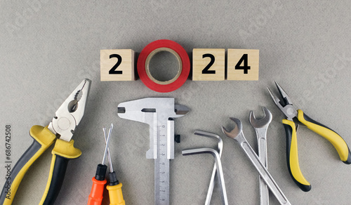 2024 on gray background with various tools. Wooden cubes with numbers 2024 on a gray background