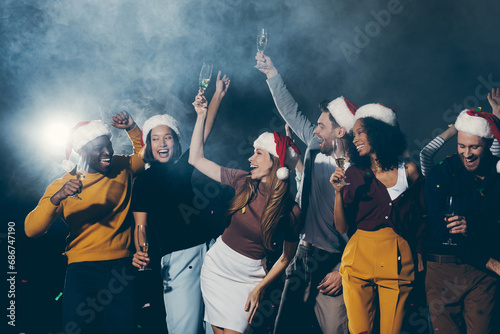 Group of young people dancing and smiling while celebrating New Year in night club together