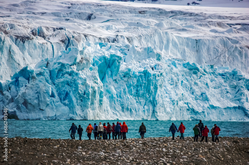 Ecotourists near a blue ice glacier above Krossfjord; Spitsbergen, Svalbard Archipelago, Norway photo
