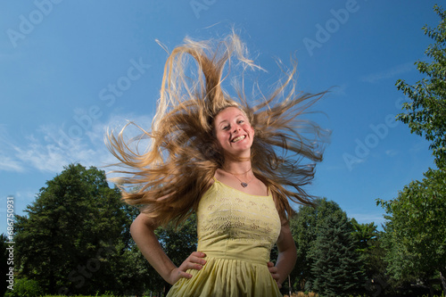 Teenage girl's blonde hair stands up around her head as she looks down and smiles at the camera; Lincoln, Nebraska, United States of America