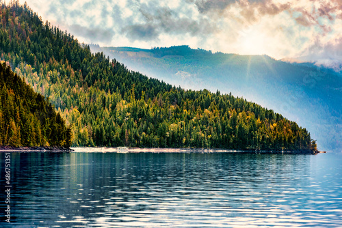 Houseboat parked on Shuswap Lake in autumn with sunrays over the mountains, British Columbia, Canada photo