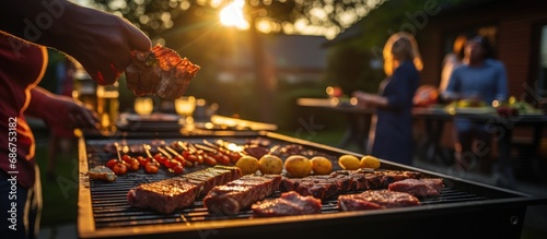 A group of people are having a party outdoors. Focus on the meat being grilled