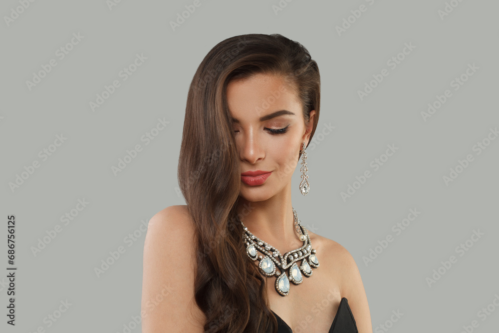 Charming jewelry woman brunette fashion model with gold diamond earning and luxury necklace posing against gray studio wall banner background
