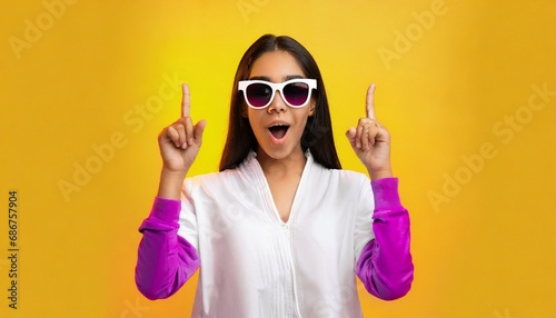 Amazed and surprised girl in sunglasses pointing fingers up.