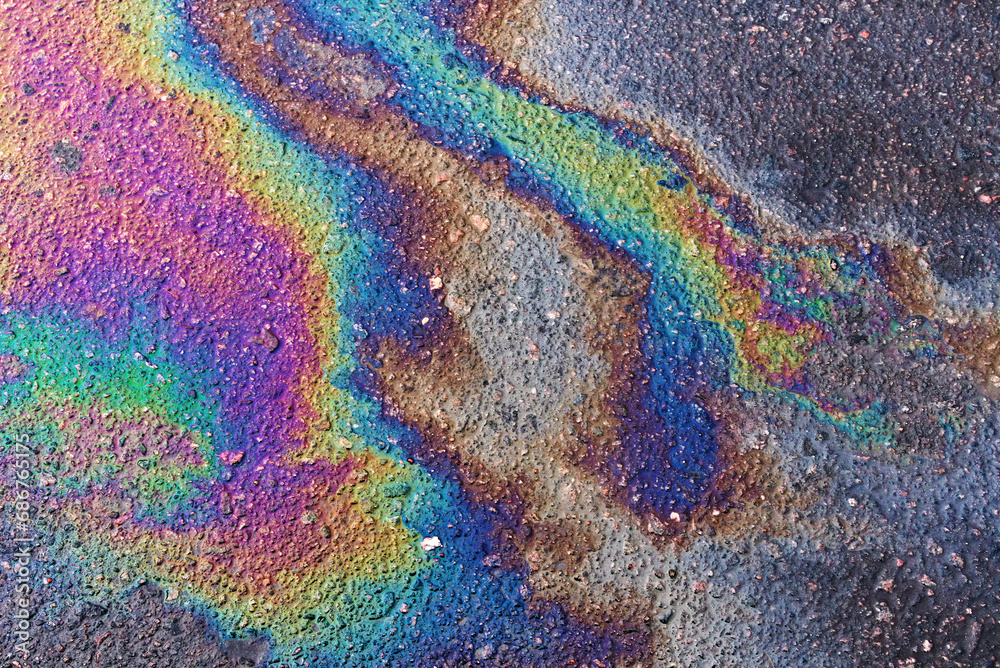 Gasoline spot on wet asphalt. Multi colored oil spill on asphalt road, abstract background, texture