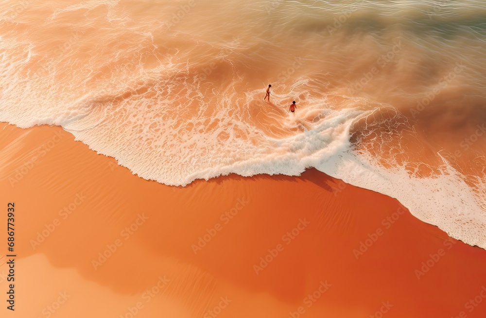 aerial view of a beautiful orange sand beach with two friends taking a dip in the water