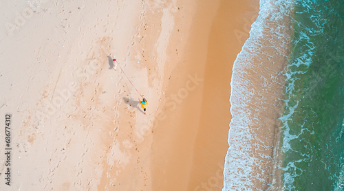 Aerial high angle shot of young woman walking with the dog along the seaside. Stunning seascape. #686774312