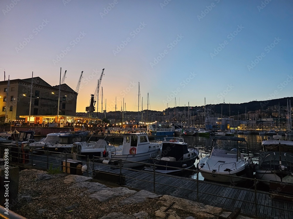 Genova, Italy - August 8, 2023: High angle view of Genoa city with sea view and yachts under the bright sun in natural background.Beautiful sunset over the city.